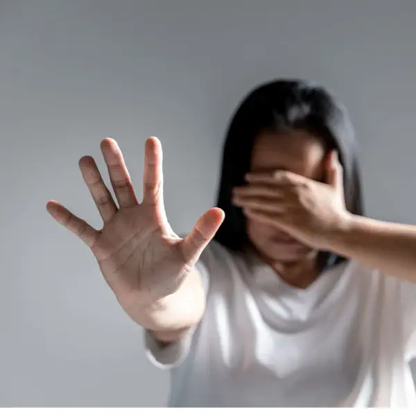 Mujer con una mano tapando sus ojos y la otra mano extendida hacia el frente