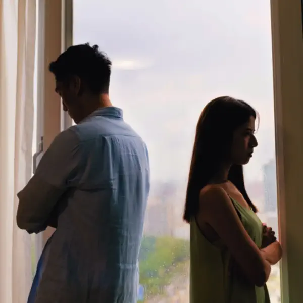 pareja frente a una ventana, de pie, de espalda con brazos cruzados