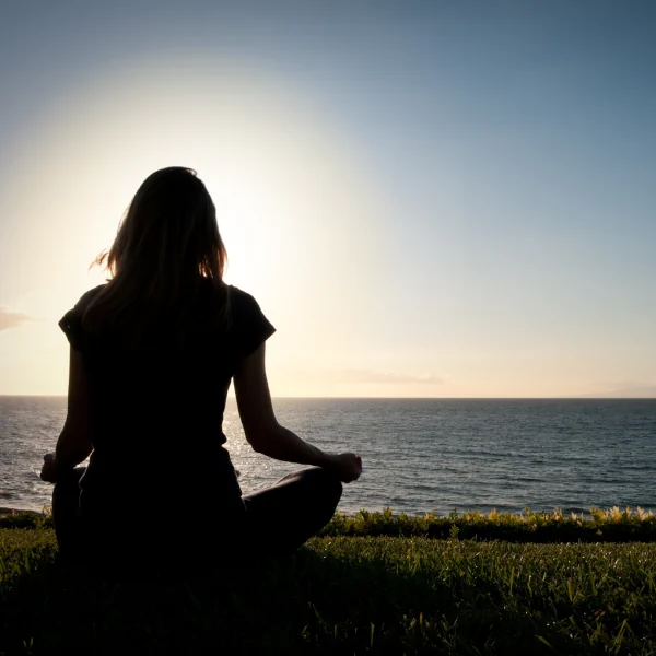 Mujer sentada frente al mar, mirando el horizonte